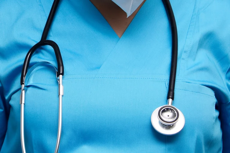 Stetoskop oko vrata doktorice u plavoj medicinskoj kuti – vizualni prikaz važnosti medicinskog pregleda prije nagađanja o simptomima i odabira laboratorijske pretrage za žene